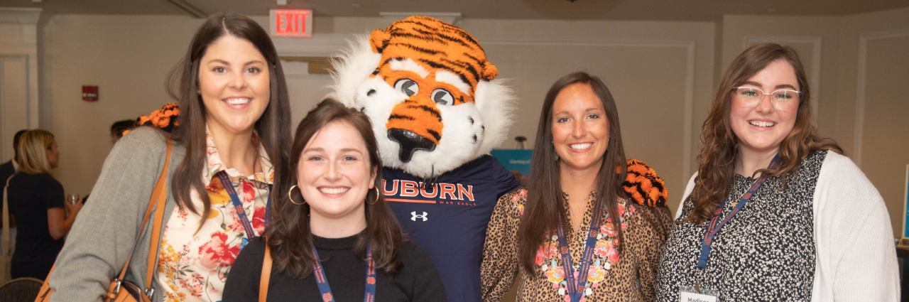 A group of four women posing with Aubie the Tiger